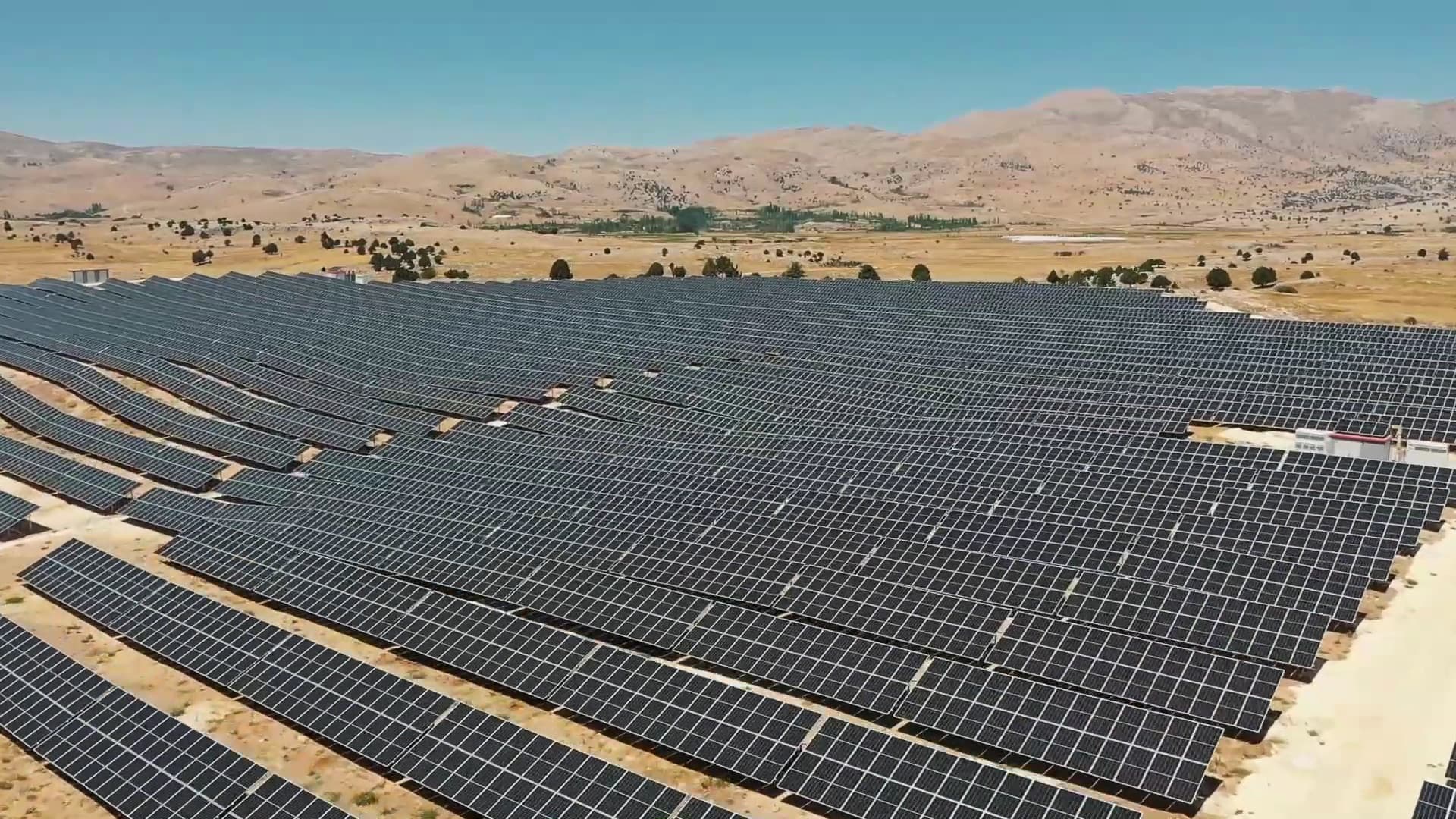 Antalya'daki güneş enerji santralinin panel dizileri, arkada dağ silsilesi, havadan görünüm